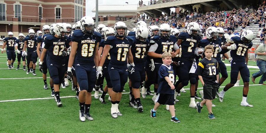 Fifth graders Wyatt Keenan and Nicholas Buellers proudly lead the varsity football team.