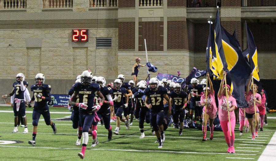 Varsity football runs out onto the field at the Berry Center.