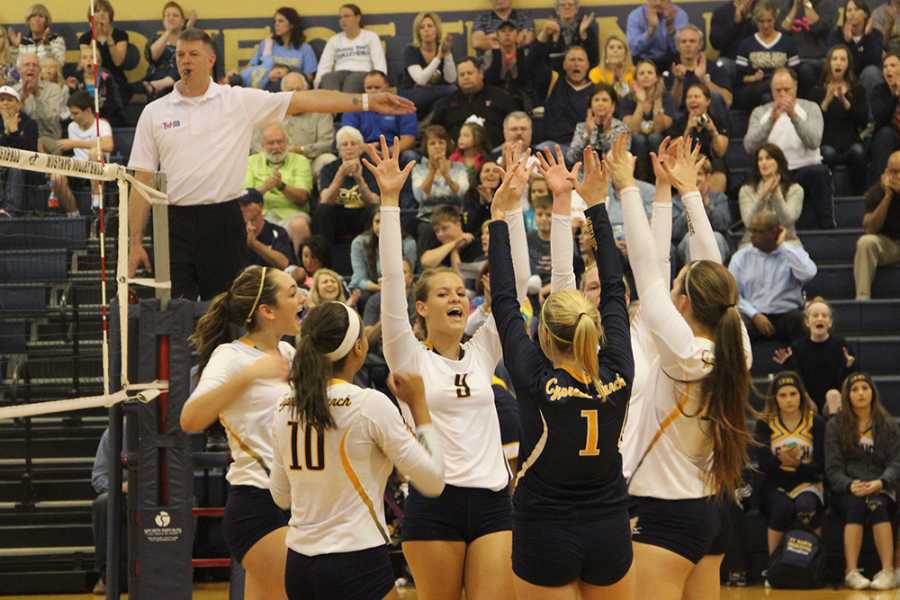 The Volleyball team celebrates on the court after scoring a point.