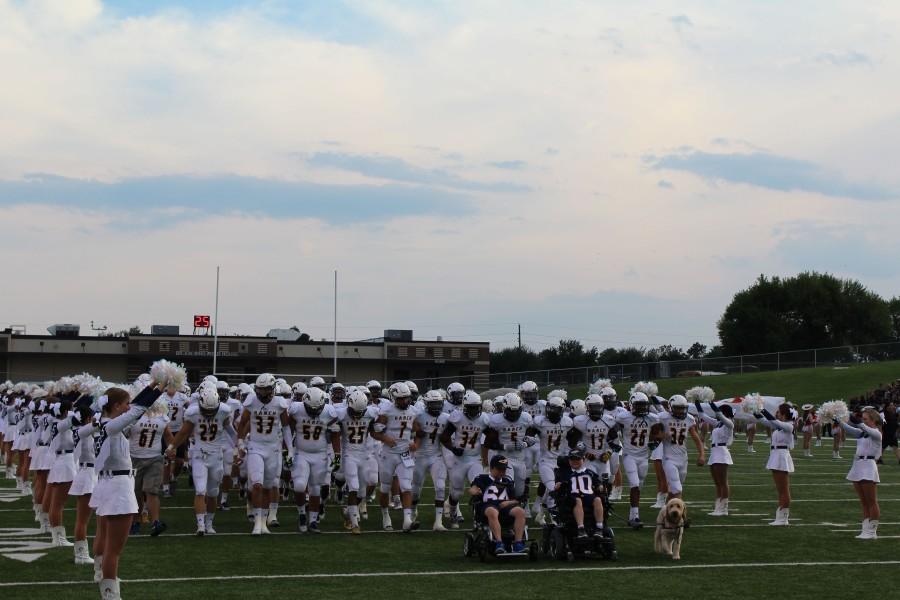 Buellers and Keenan lead the Cy Ranch varsity football team onto the field.