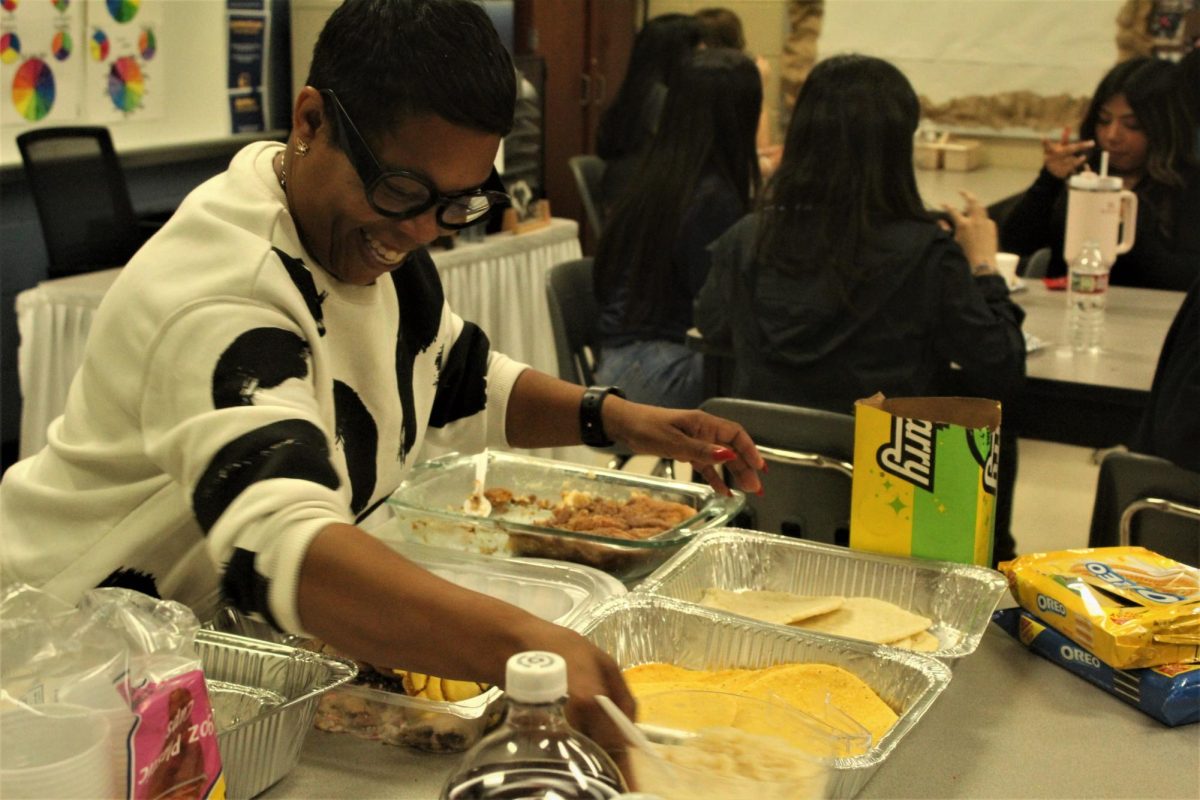 Cosmetology teacher Mrs. Brooks passes out food to the students during the social.