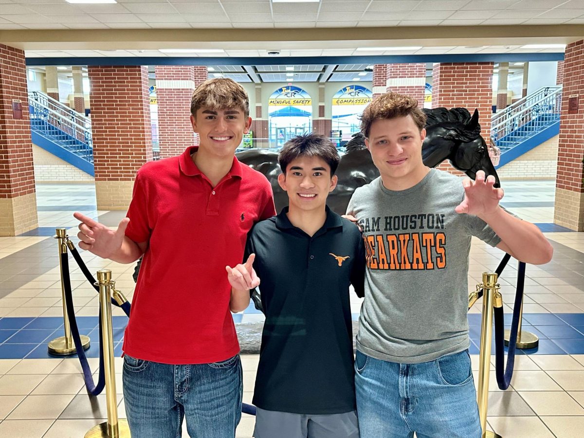 Seniors Bryce Schlosser-Bradford, Kyle Bui and Sean Howlett pose in front of the Mustang after being awarded their full-ride scholarships to college.